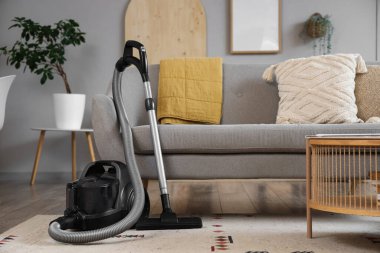 Oturma odasındaki kanepenin yanındaki modern elektrikli süpürge.