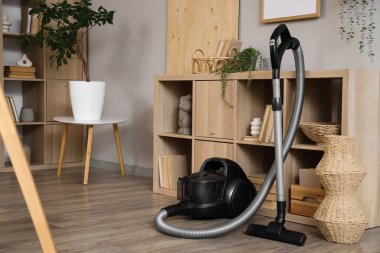 Oturma odasının iç tarafındaki raf yakınında elektrikli süpürge var.