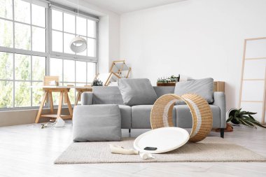 Depremden sonra kanepe ve ters dönmüş masa olan dağınık bir oturma odası.