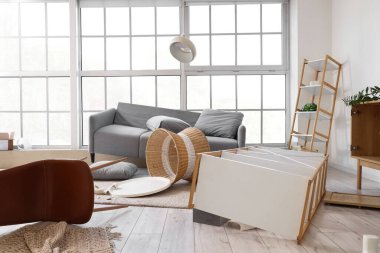 Kanepeli dağınık bir oturma odası. Depremden sonra masa ve raflar alt üst olmuş.