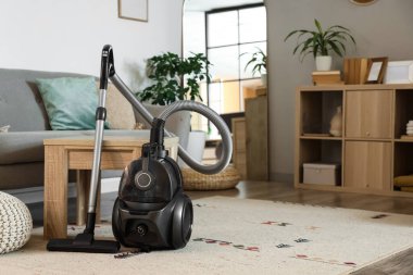 Oturma odasındaki kahve masasının yanındaki elektrikli süpürge.