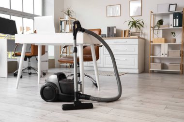 Ofisin iç tarafındaki masanın yanındaki elektrikli süpürge.