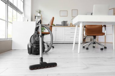 Elektrik süpürgesi ve masalarla birlikte ofis içi.