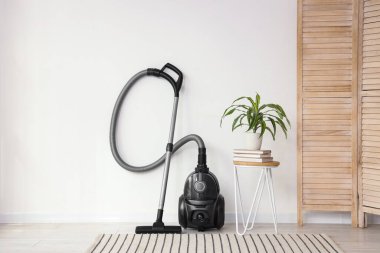Oda içindeki ışık duvarının yanındaki modern elektrikli süpürge.