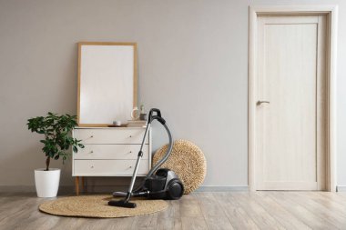 Elektrik süpürgesi, çekmecesi ve puf olan oturma odasının içinde.