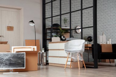 Karton kutuları, eşyaları ve monitörleri taşınma gününde filme sarılı modern ofisin içi.