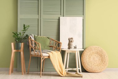 Oturma odasının içinde yeşil katlı ekran, koltuk ve masa.