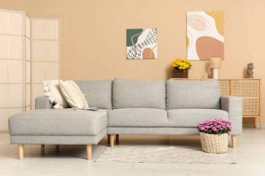 İçinde kanepe ve kasımpatı çiçekleri olan oturma odası.