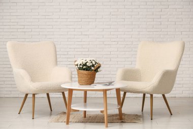 Oturma odasının içinde koltuklar ve kasımpatı çiçekleri var.