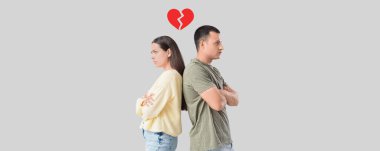 Sad young couple after quarrel on grey background clipart