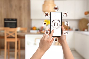 Akıllı ev otomasyonunun açık uygulaması olan cep telefonu mutfakta ekranda.