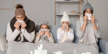 Kanepede oturan burunları akan hasta bir aile.