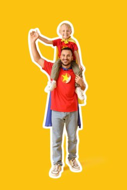 Sarı arka planda süper kahramanlar gibi giyinmiş küçük oğluyla mutlu bir baba.
