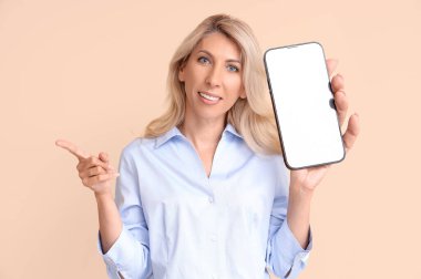 İş kadını elinde bej arka planda boş ekranlı cep telefonu tutuyor. Tasarım için pankart