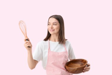 Pembe arka planda fırça ve kase ile önlüklü güzel bir genç kadın.