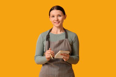 Sarı arka planda not defteri olan güzel bir garson kız.