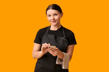 Sarı arka planda cep telefonu olan güzel bir garson kız.