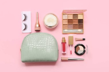 Pembe arka planda farklı makyaj ürünleri olan kozmetik çanta.