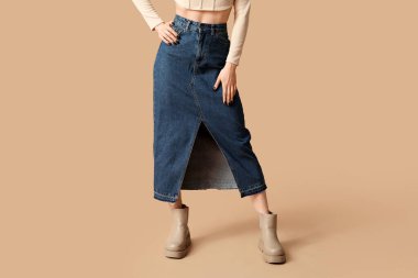 Güzel genç bayanın bacakları bej arka planda mavi uzun kot etek giyiyor.