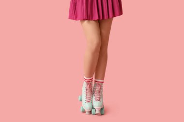 Pembe arka planda paten giyen genç kadınların bacakları.