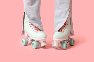 Pembe arka planda paten giyen genç kadınların bacakları.