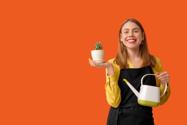 Sulama kabı ve turuncu arka planda bitki yetiştiren güzel bir kadın.