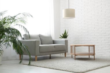 Gri kanepe, masa ve ışık perdeleri olan şık bir oturma odası.