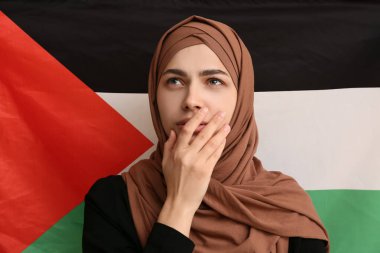Filistin bayrağına karşı arka plan olarak güzel, üzgün, Müslüman bir kadın. Üzüntü konsepti