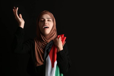 Filistin bayrağıyla siyah arka planda ağlayan üzgün Müslüman bir kadın. Üzüntü konsepti