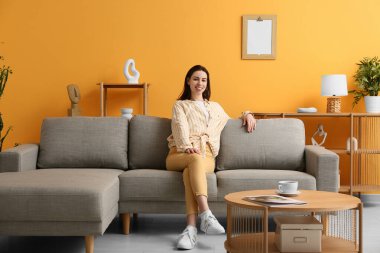 Oturma odasındaki kanepede oturan genç kadın.