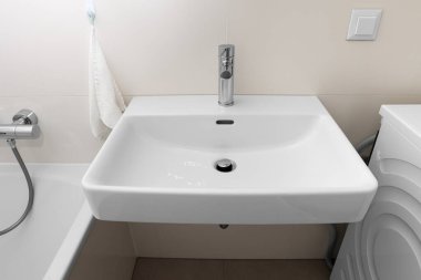 Banyoda gümüş musluğu olan beyaz lavabo.