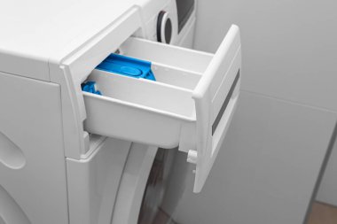 Odada açık deterjan çekmecesi olan modern çamaşır makinesi, yakın plan.