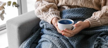 Evde kelebek çiçeği çayı içen bir kadın, yakın plan.