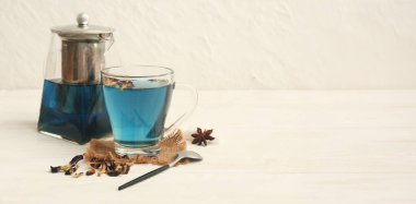 Bir fincan kelebek çiçeği çayı ve hafif zemin üzerinde çaydanlık ve metin için yer var.