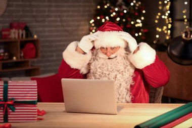 Noel Baba evde dizüstü bilgisayar kullanıyor.