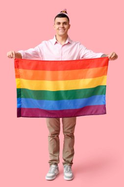 Pembe arka planda LGBT bayrağı olan Noel Baba şapkalı genç adam.