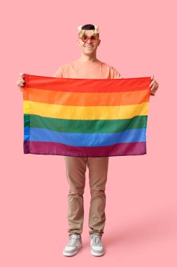 Pembe arka planda LGBT bayrağı olan Noel gözlüklü genç adam.