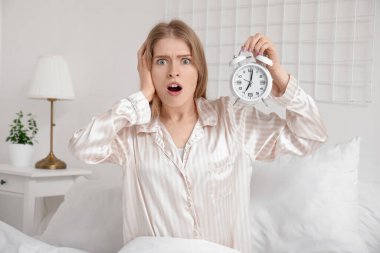 Evde elinde çalar saatle şok olmuş genç bir kadın.