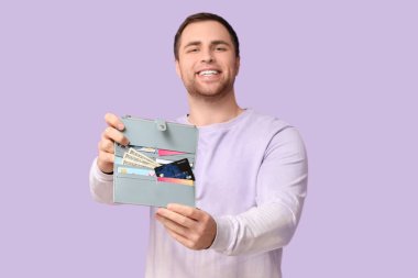 Leylak arka planında kredi kartları olan genç bir adam.