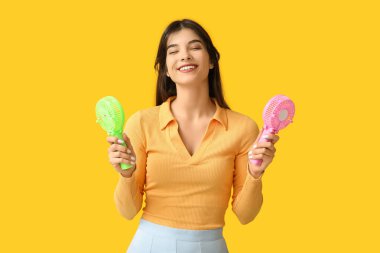 Sarı arka planda mini fanları olan genç bir kadın.