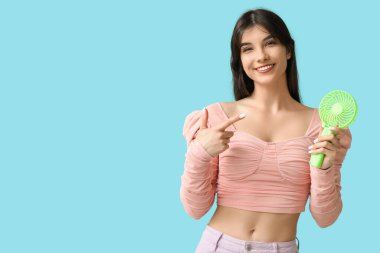 Mavi arka planda mini fanı olan genç bir kadın.