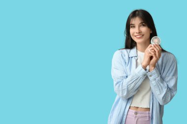 Mavi arka planda mini fanı olan genç bir kadın.