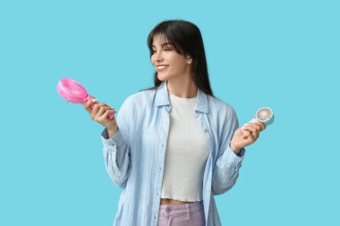 Mavi arka planda mini hayranları olan genç bir kadın.