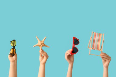 Şık güneş gözlüklü kadın elleri, küçük iskemle ve mavi arka planda deniz yıldızı.