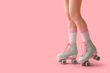 Pembe arka planda paten giyen genç kadınların bacakları.