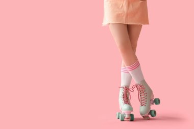 Young woman in roller skates on pink background