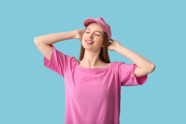 Mavi arka planda zarif pembe şapkalı güzel bir genç kadın.