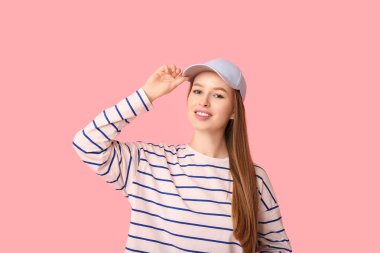 Happy young woman in stylish blue cap on pink background