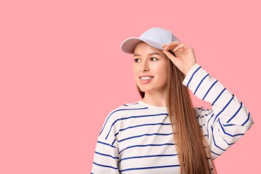 Happy young woman in stylish blue cap on pink background