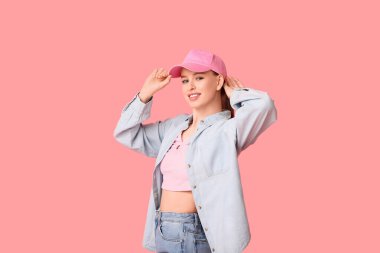 Pembe arka planda şık şapkalı mutlu genç kadın.